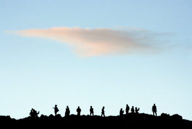 silhouette of people standing on rock